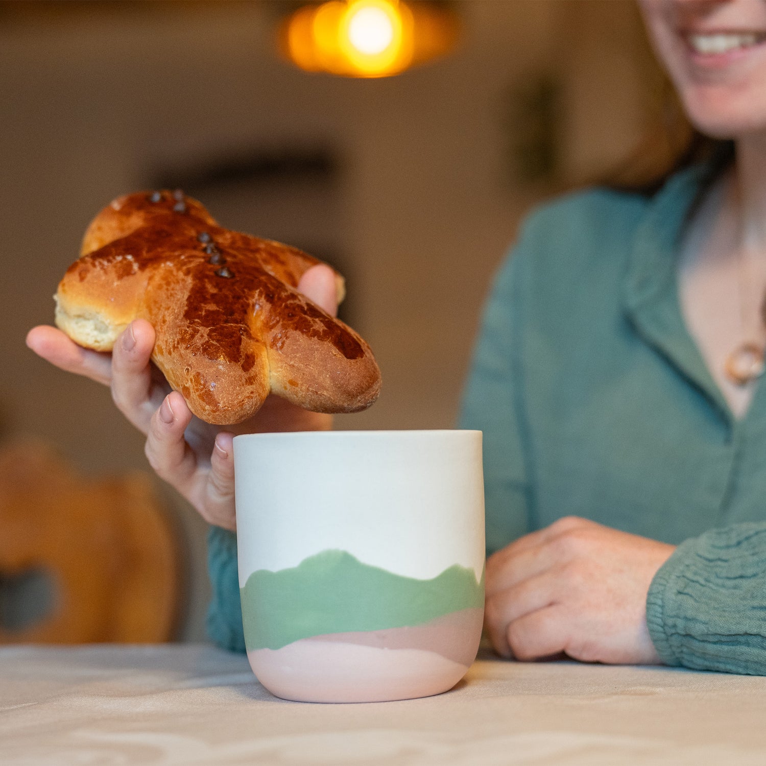 Tasse à thé fabriquée en France artisanalement, en porcelaine, motif montagne des Vosges, couleurs douces pastels, brioche manala bonhomme aux pépites de chocolat
