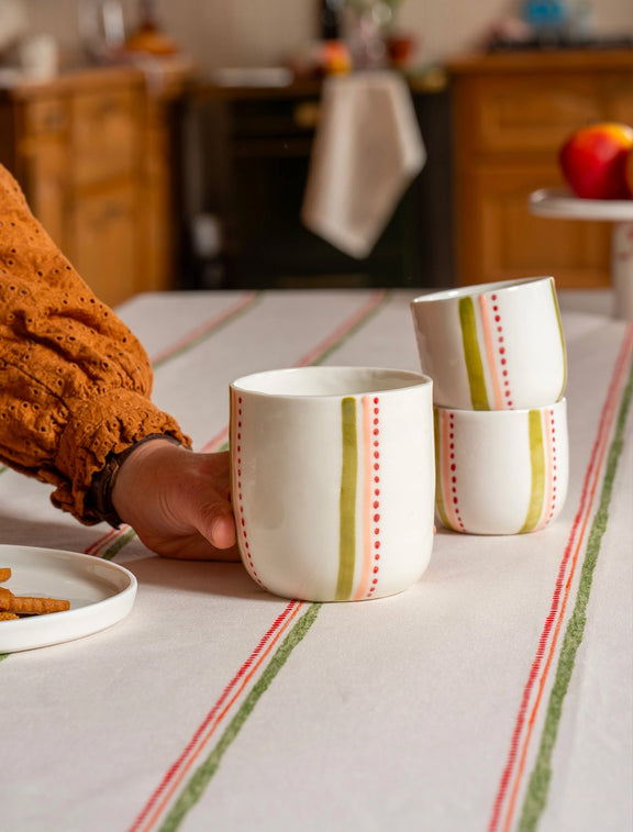 Tasses à thé et à café en porcelaine artisanales fabriquées en France, motif rayures colorées, sur nappe rayée