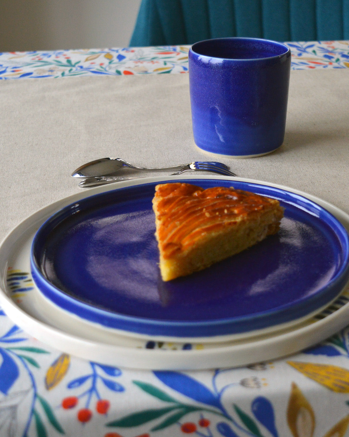 Porcelaine artisanale fabriquée en France, tasse à thé bleue Maison Primavera avec assiettes à motif et bleue sur linge de table français.
