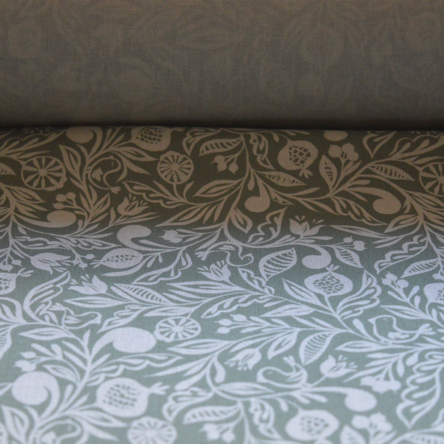 Zoom sur tissu en coton et en lin fabriqué en France dans les Vosges, motif blanc sur fond vert, motif floral Alsace