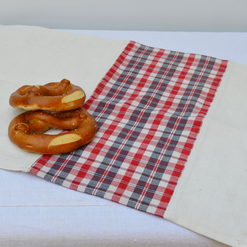 Torchon en kelsch rouge et bleu et en lin, fabriqué en France en Alsace. Sur fond blanc, avec des bretzels.